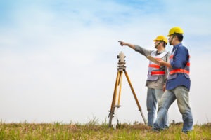 Two fieldwork land surveyors working together to produce a land survey.