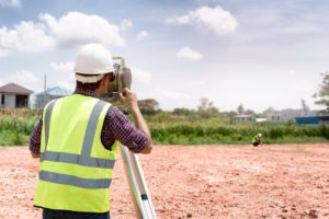 A surveyor uses professional equipment to evaluate a piece of land.