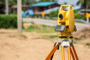 A professional surveying instrument sits on a plot of land.