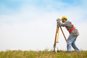 a land surveyor at work in a grass field
