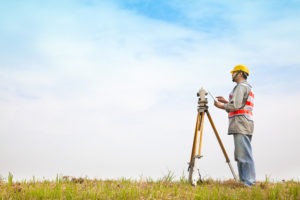a land surveyor at work in a grass field