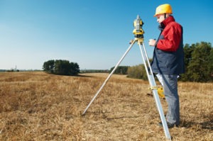 a land surveyor taking measurements in a field