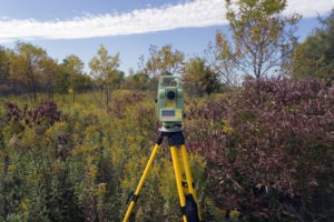 land survey equipment among trees and bushes