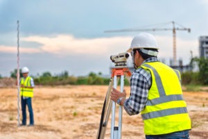 two land surveyors working on dirt lot